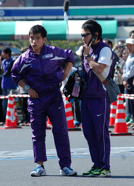高橋正仁コーチとともに出番を待つ２区馬越幹成(左)＝第１中継地点で
